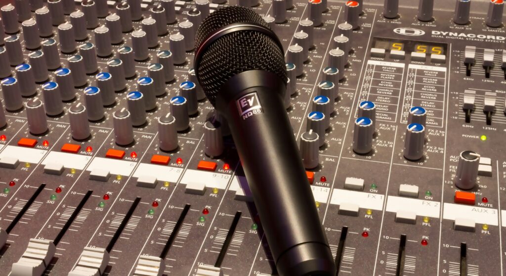 Handheld microphone sitting on a sound mixer